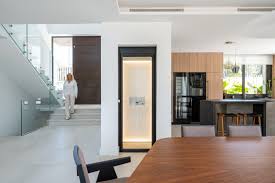 Slim built-in home elevator beside a staircase in a modern house interior